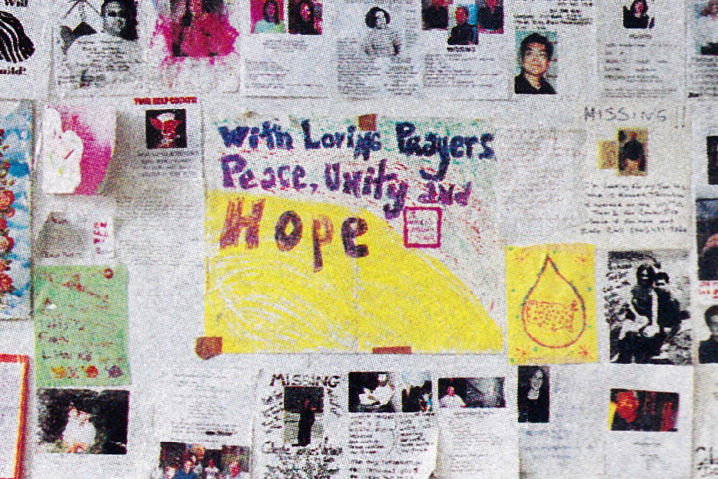Close-up of a wall papered with flyers for missing 9/11 victims, together with hand-drawn messages of hope and unity.