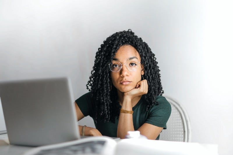 Young woman at laptop wearing glasses, looking bored and longing to be a writer. Young woman at laptop wearing glasses, looking bored and longing to be a writer.