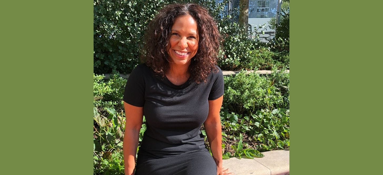 Rachel Hughes, seated outside, in a black dress, smiling at the camera