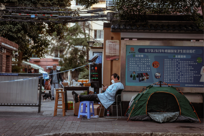 A medical worker rests next to a quarantined area in Shanghai. Some experts see parallels between China’s zero-Covid policy and the infamous one-child policy 