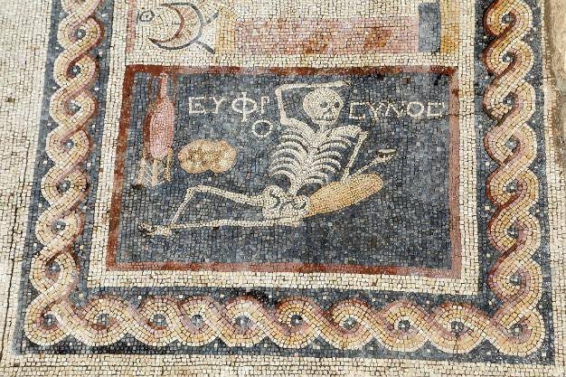 Picture of an ancient Turkish skeleton mosiac that says "be cheerful! Enjoy your life!"