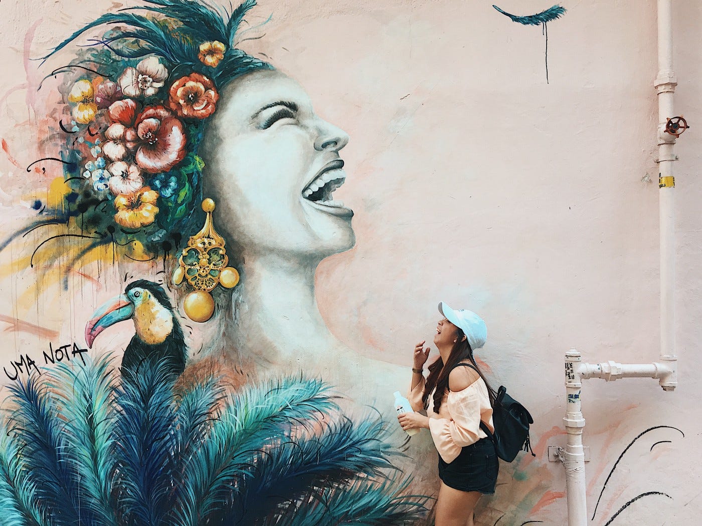 Woman laughing at a large mural of another woman laughing.