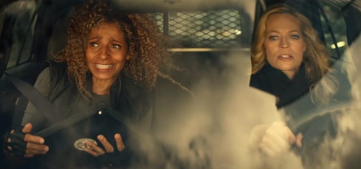 This image shows Raffi Musiker (played by Michelle Hurd) and Seven of Nine (played by Jeri Ryan) sitting in the front seats of an LAPD vehicle that Seven drives at high speed through the city's streets. Raffi sits in the passenger's seat (on the left) and Seven sits in the driver's seat (on the right). This image shows Raffi Musiker (played by Michelle Hurd) and Seven of Nine (played by Jeri Ryan) sitting in the front seats of an LAPD vehicle that Seven drives at high speed through the city's streets. Raffi sits in the passenger's seat (on the left) and Seven sits in the driver's seat (on the right).