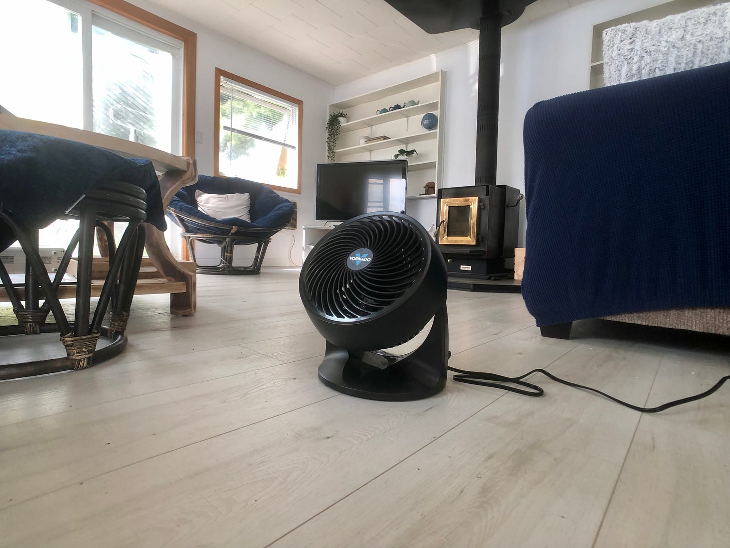 An electric fan on the floor of a cottage living room.