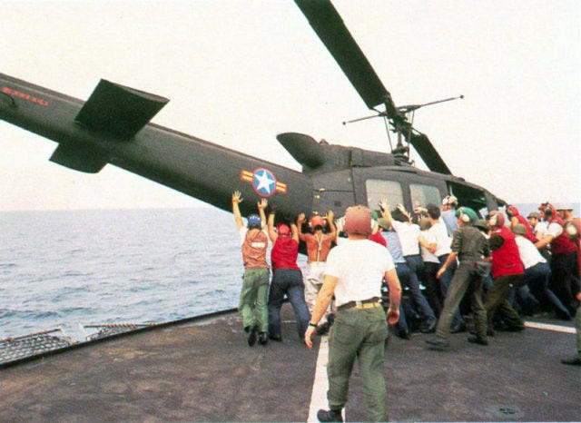 A South Vietnamese UH-1H is pushed overboard to make room for a Cessna O-1 landing