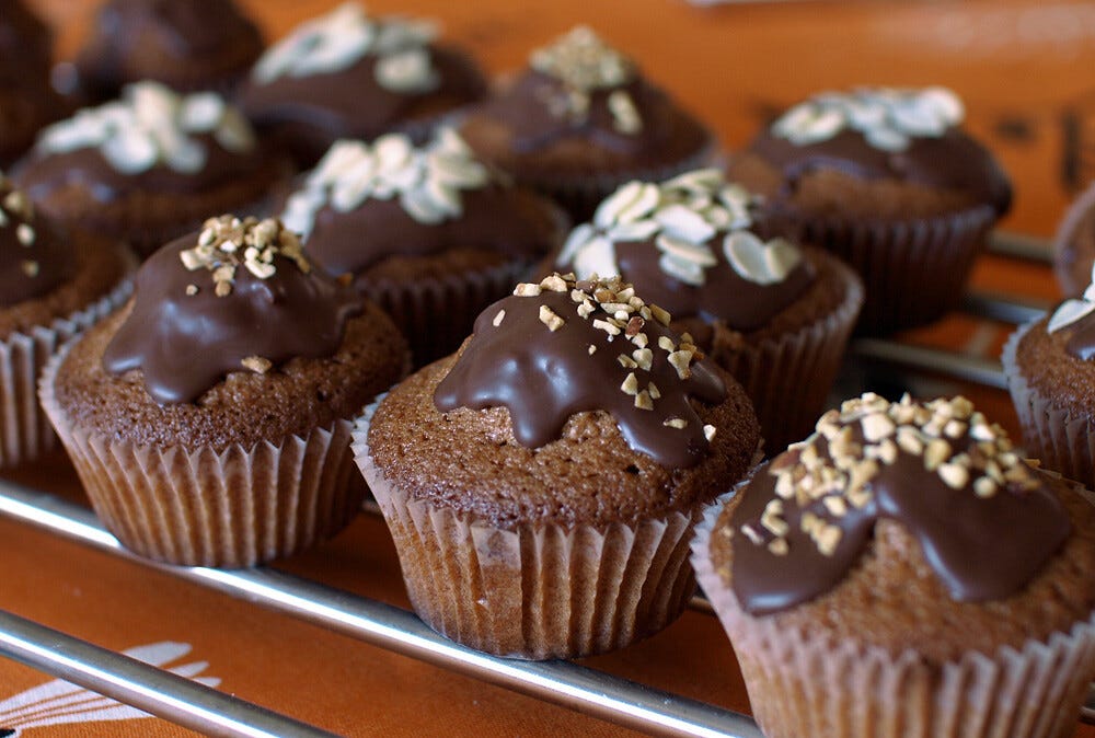 A batch of muffins with chocolate frosting and chopped nuts on top. "Chocolate muffins" by Roberta Romagnoli / wererabbit is licensed under CC BY-NC-ND 2.0 