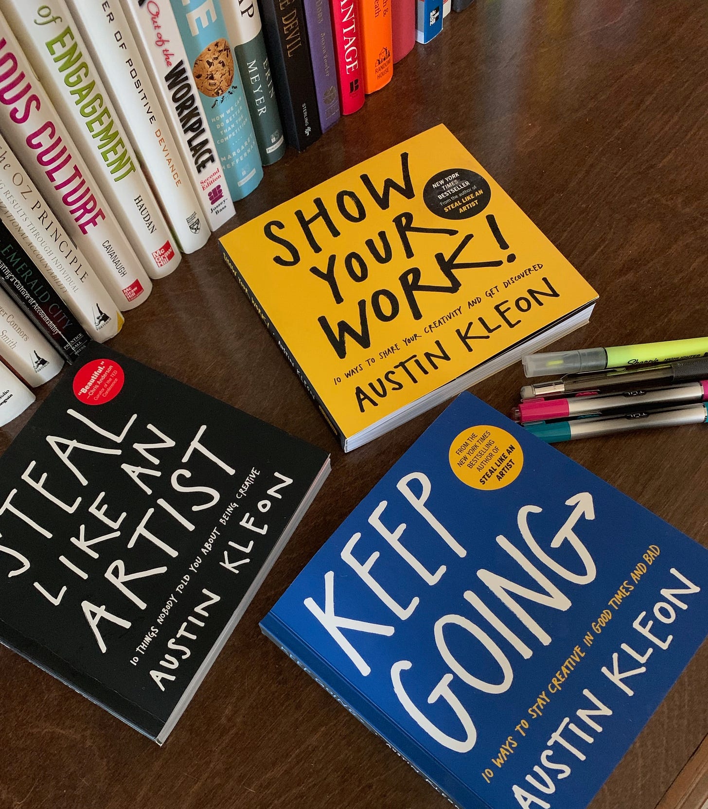 three books by Austin Kleon sitting on a desk with pens and markers