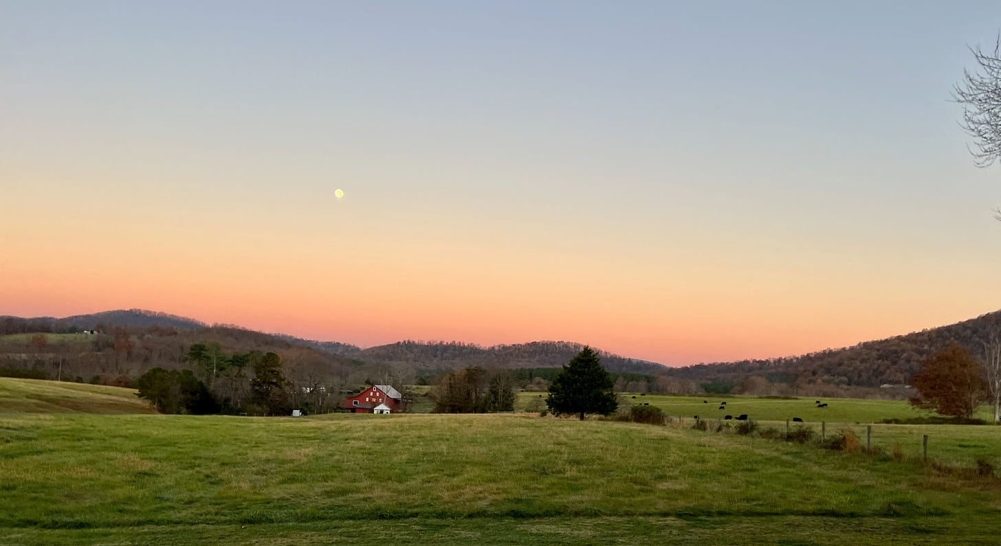 Moon setting over fields and mountains