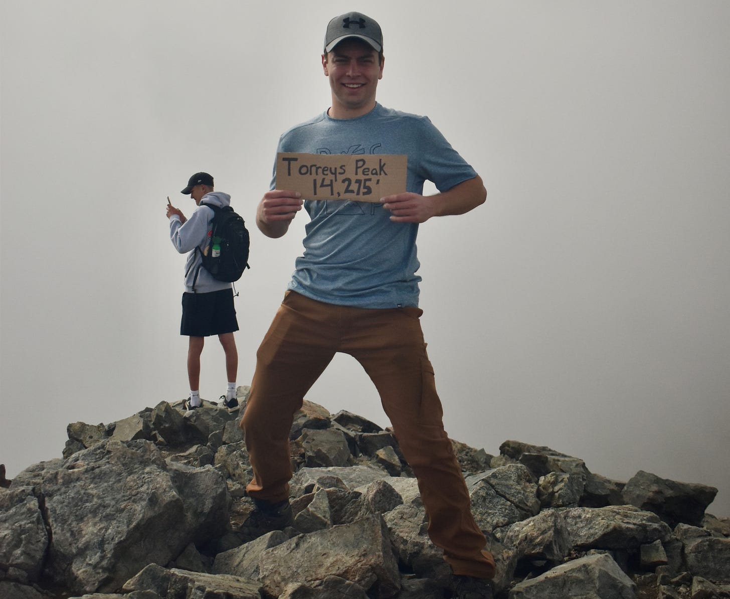 me, standing atop Torreys peak. The sky behind me is foggy.