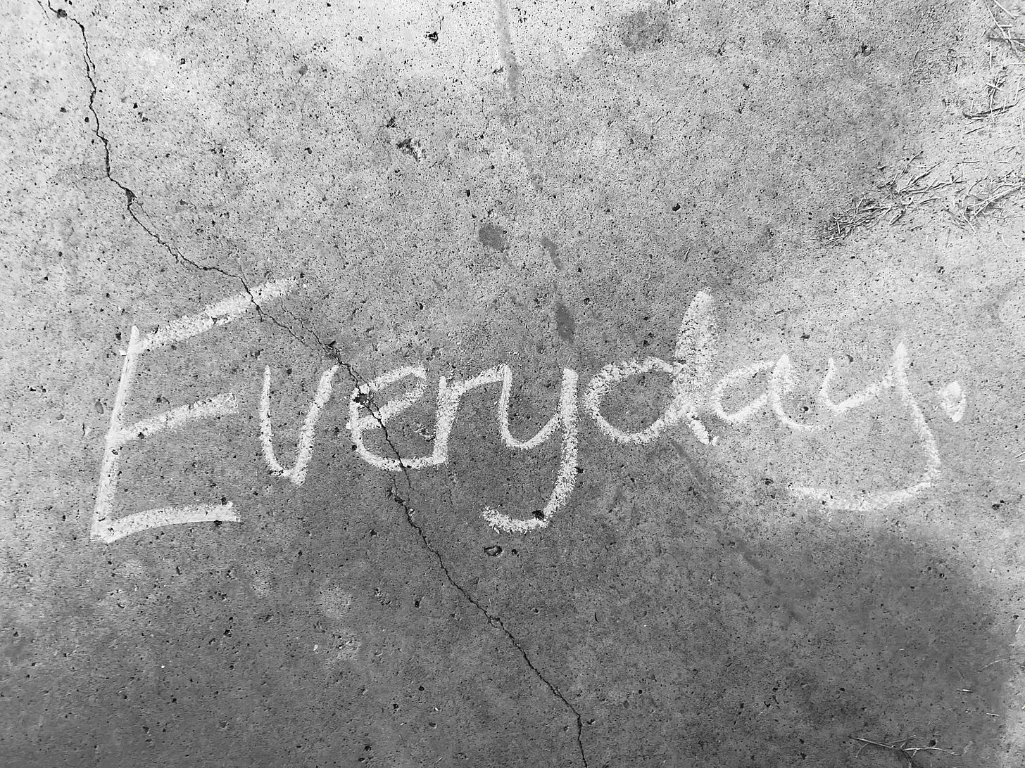 black and white photo of "everyday" written on concrete with chalk