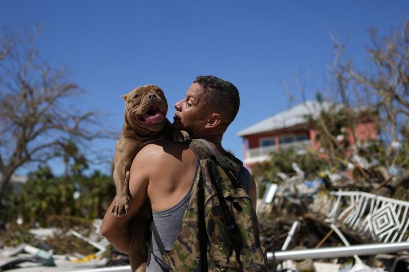 Eduardo Tocuya carries a dog he recovered in hopes of reuniting it with its owners, two days after the passage of Hurricane Ian, in Fort Myers Beach, Fla., Friday, Sept. 30, 2022. (AP Photo/Rebecca Blackwell)