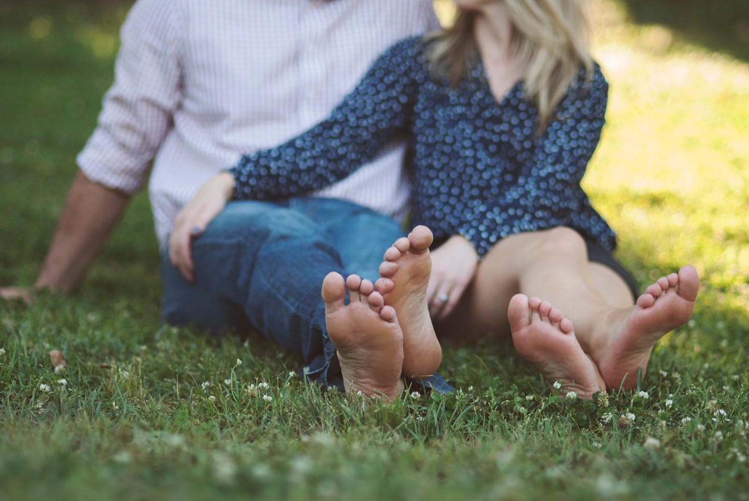 A couple sits barefoot in a summer garden.