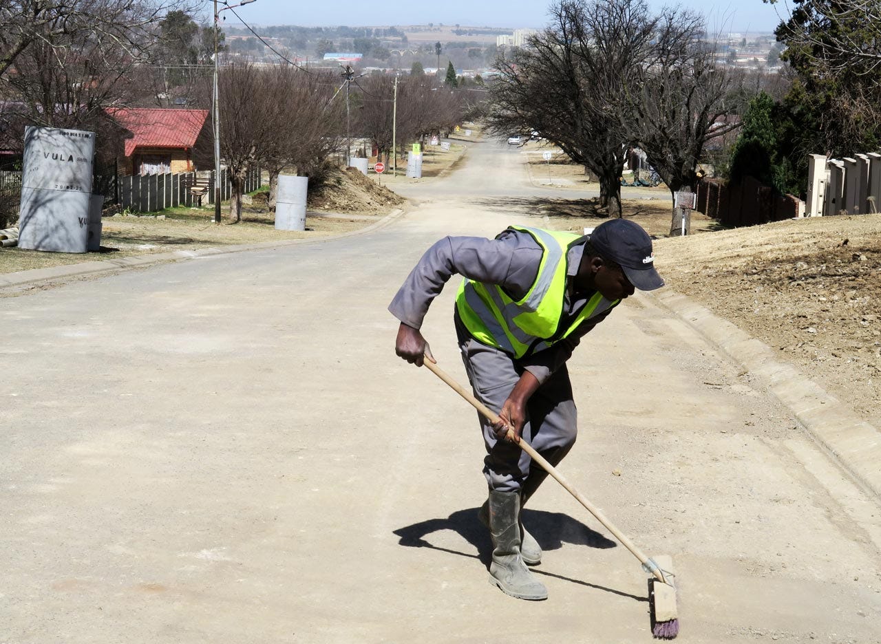 Contracted worker Vusi Langa sweeps up dirt