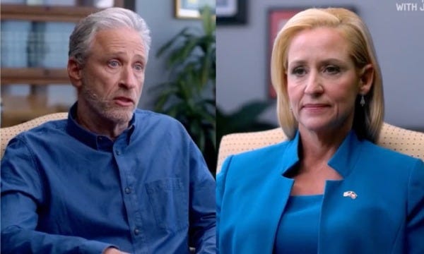 A split screen of a face-to-face interview between, on the left side, famed talk show host and comedian Jon Stewart, and on the right Leslie Carol Rutledge, the fascist Attorney General of Arkansas.