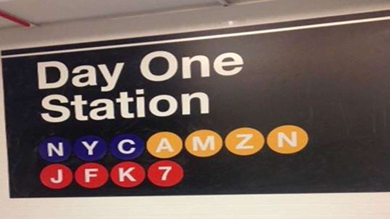 An image of a NYC subway station sign that says "Day One Station, NYC AMZN JFK7" 