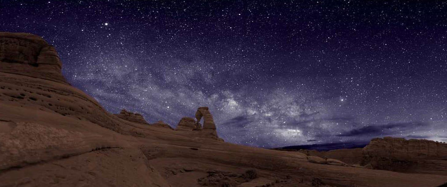Gorgeous photo of brown dunes against a purple sky dotted with stars