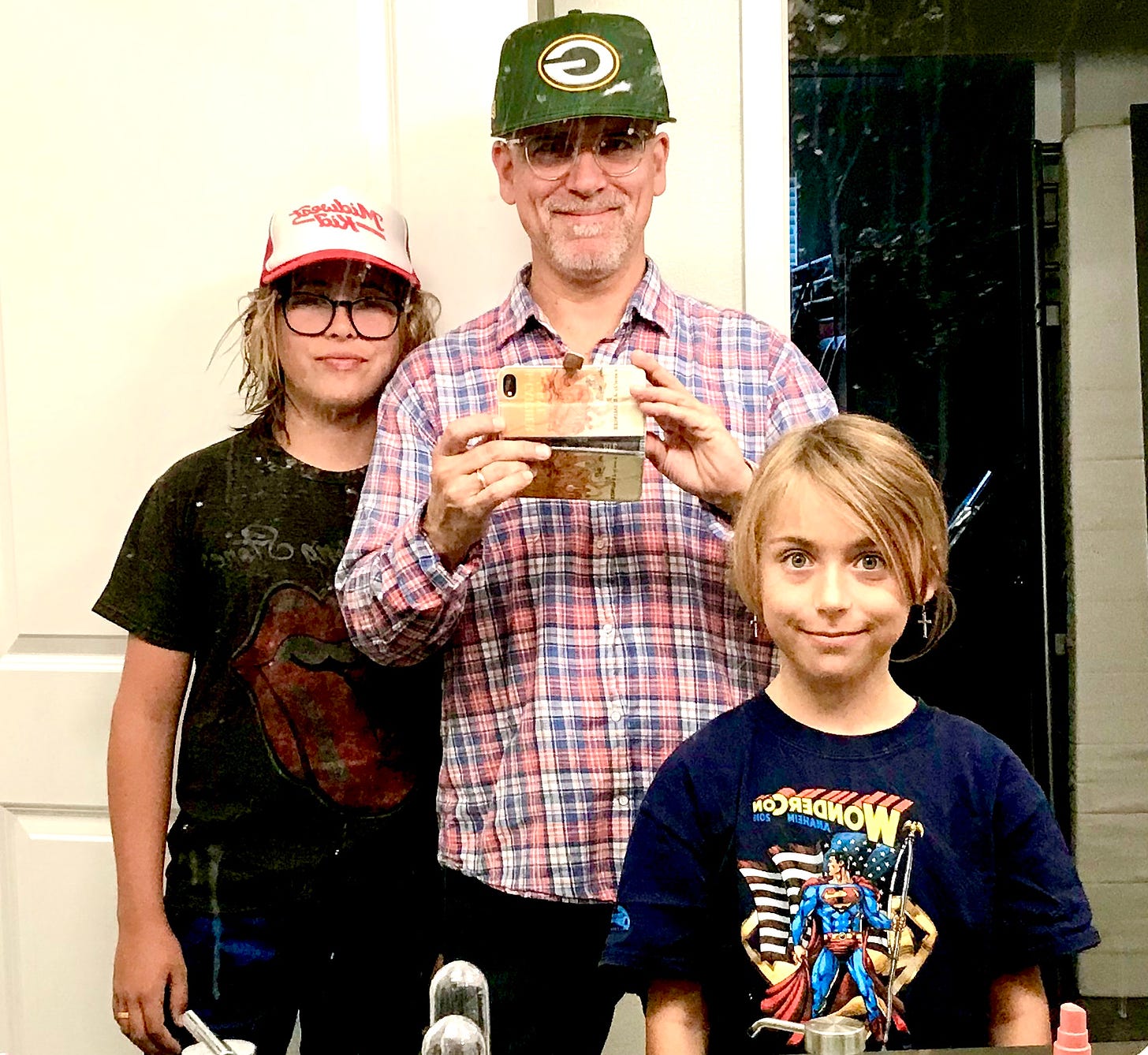 Faux Jean wears Green Bay Packers hat in mirror selfie with his kids.