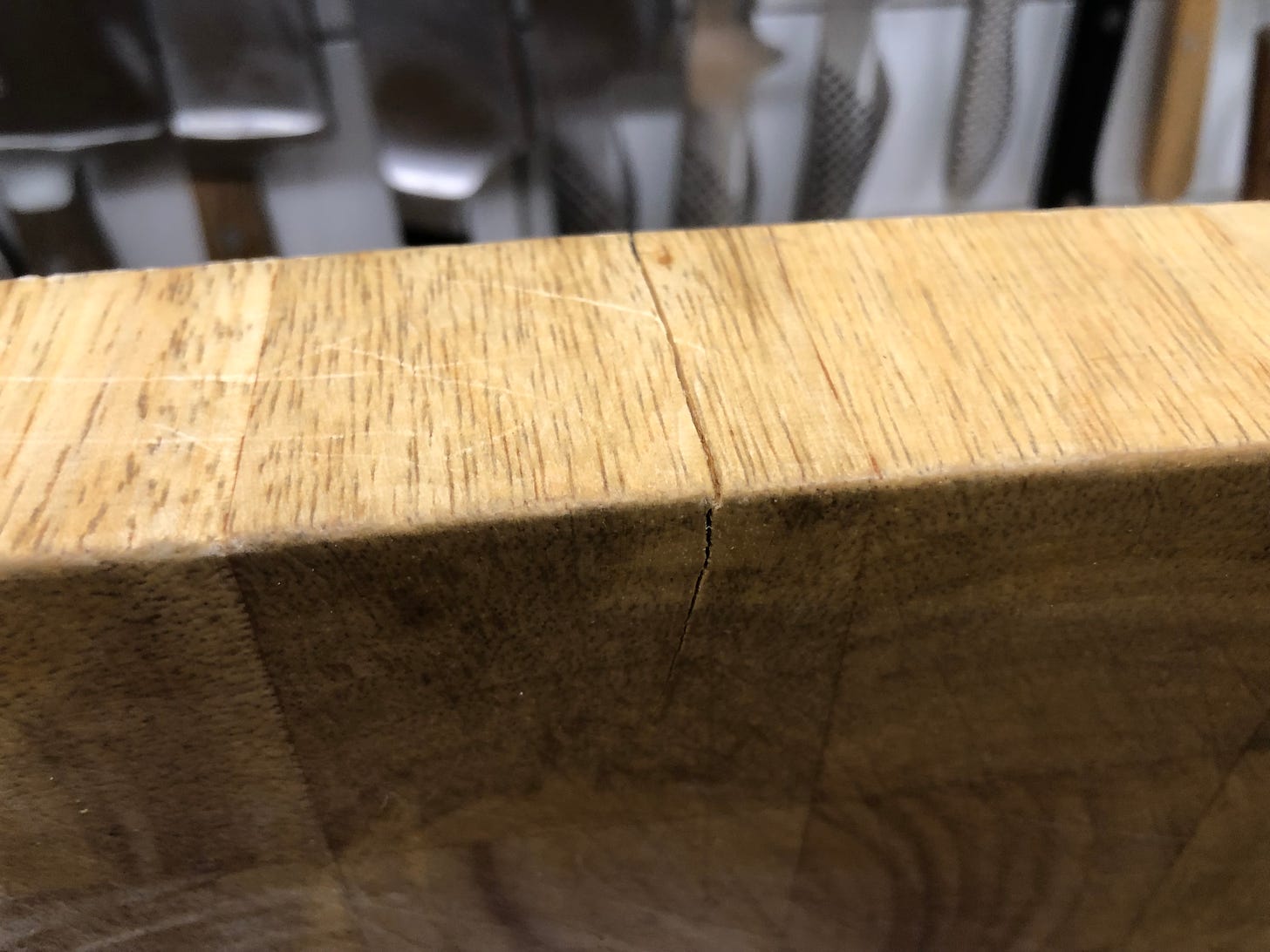 The edge of a thick cutting board with a thin crack in it