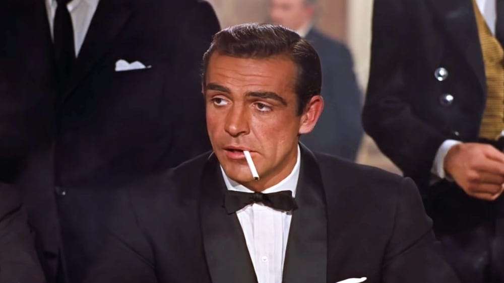 James Bond, wearing a tux, smoking a cigarette