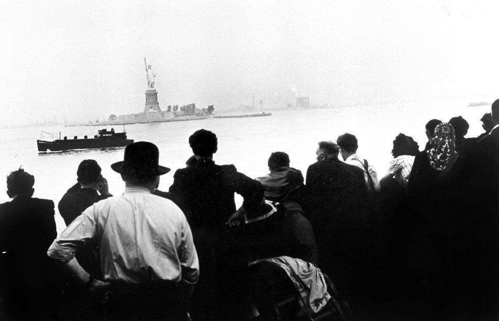 Un grupo de inmigrantes contempla la Estatua de la Libertad desde Ellis Island, 1910.