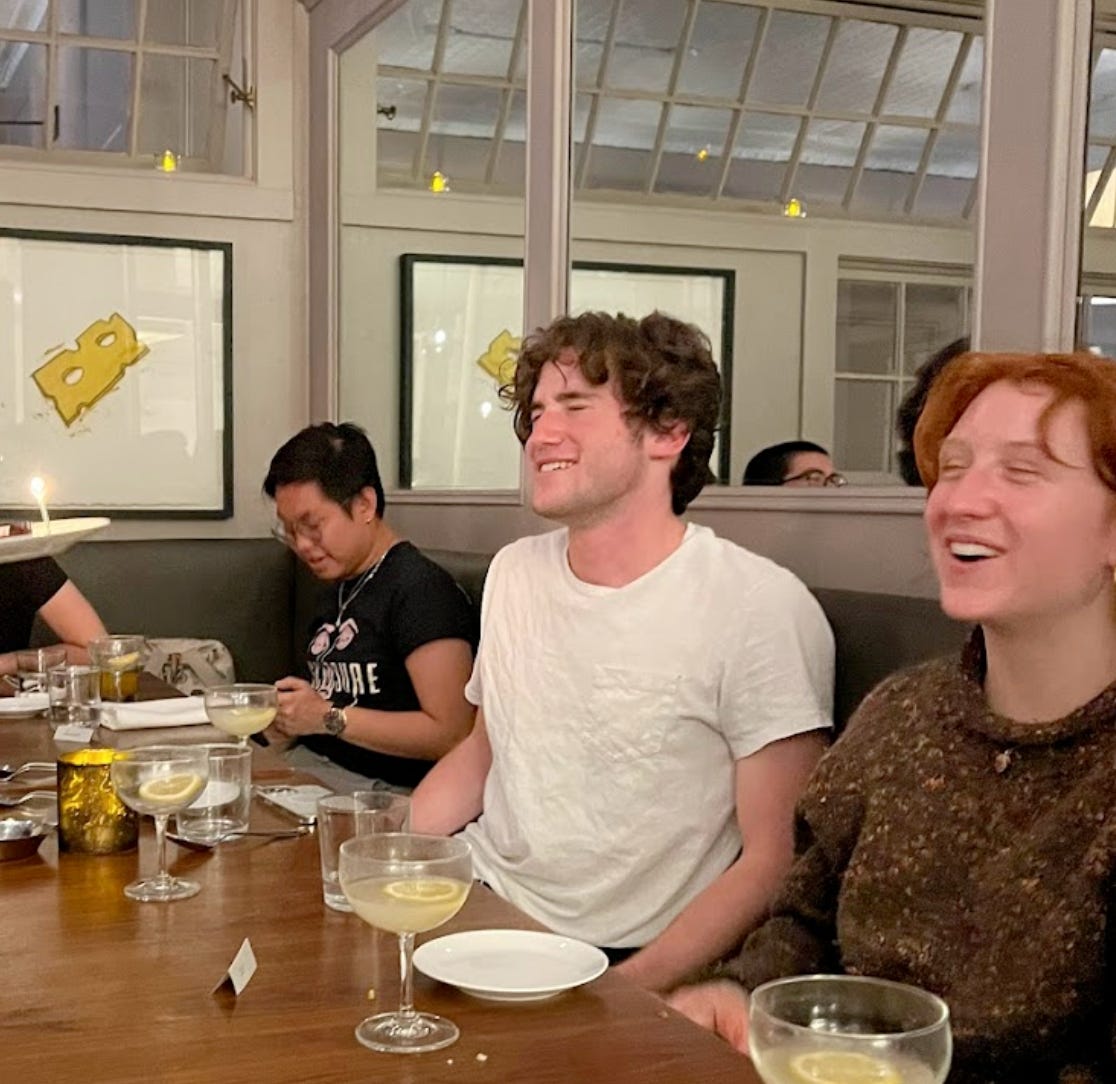 Lucas laughing at a restaurant table with friends