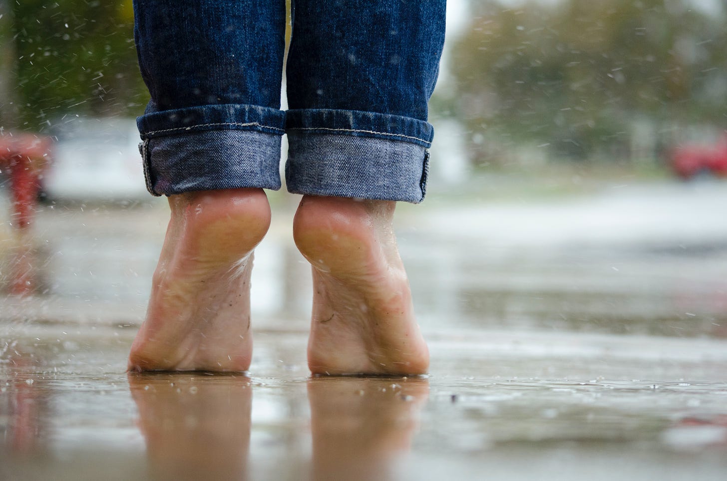 A person's bare feet outside on a rainy day.