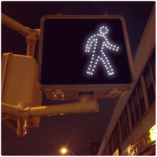 a gif of a walking sign where the icon of a person breaks free from the sign and goes out into the street
