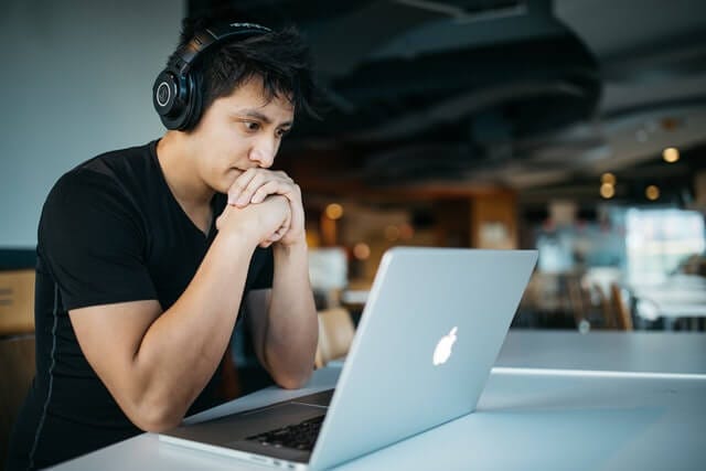 man wearing headphones looking at computer