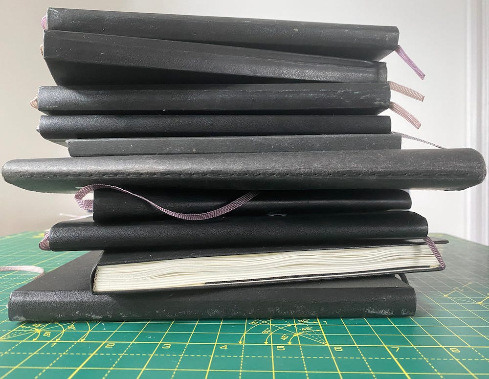 10 filled sketchbooks piled up