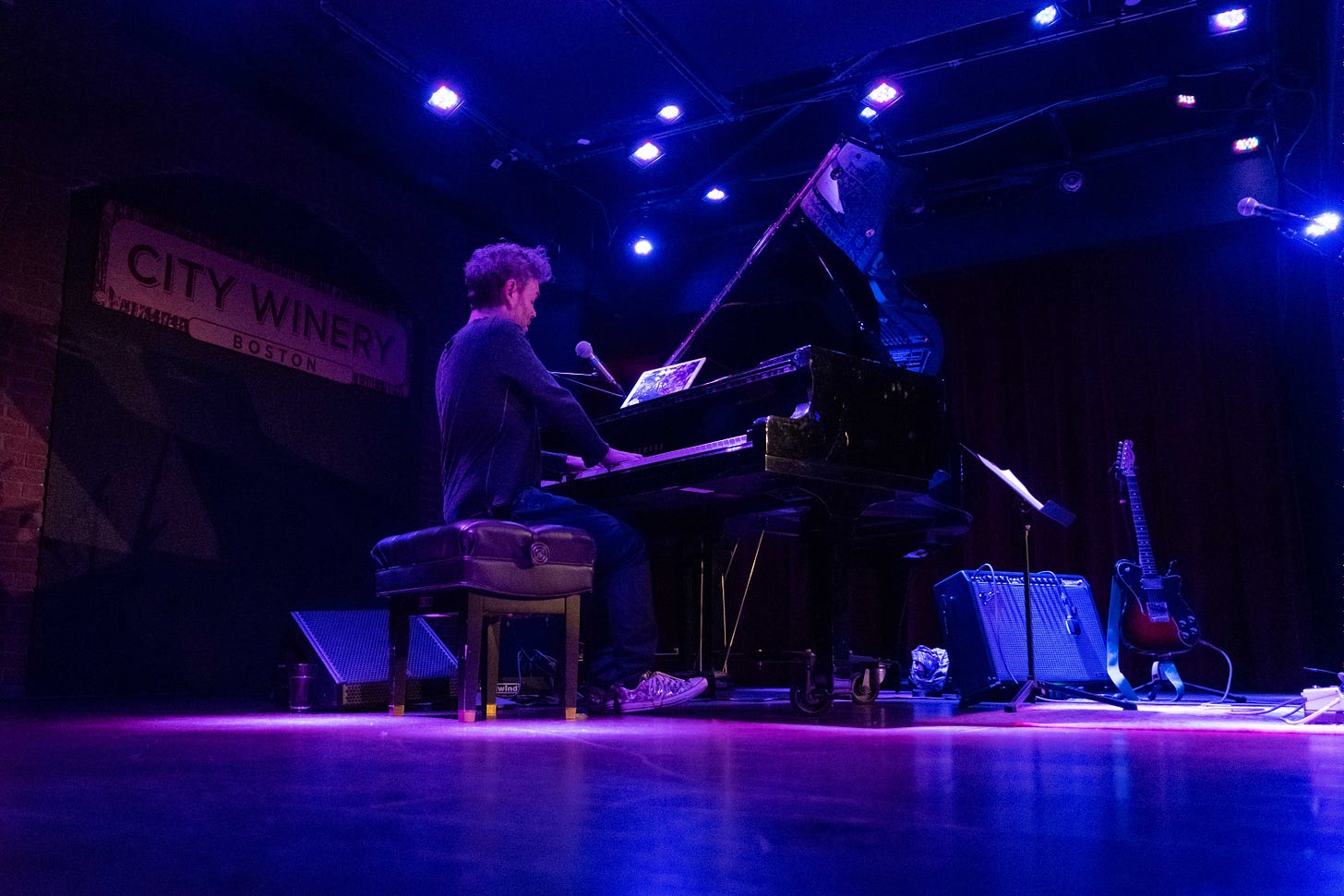 Gabriel Kahane onstage, seated at a piano, playing a concert at City Winery Boston.