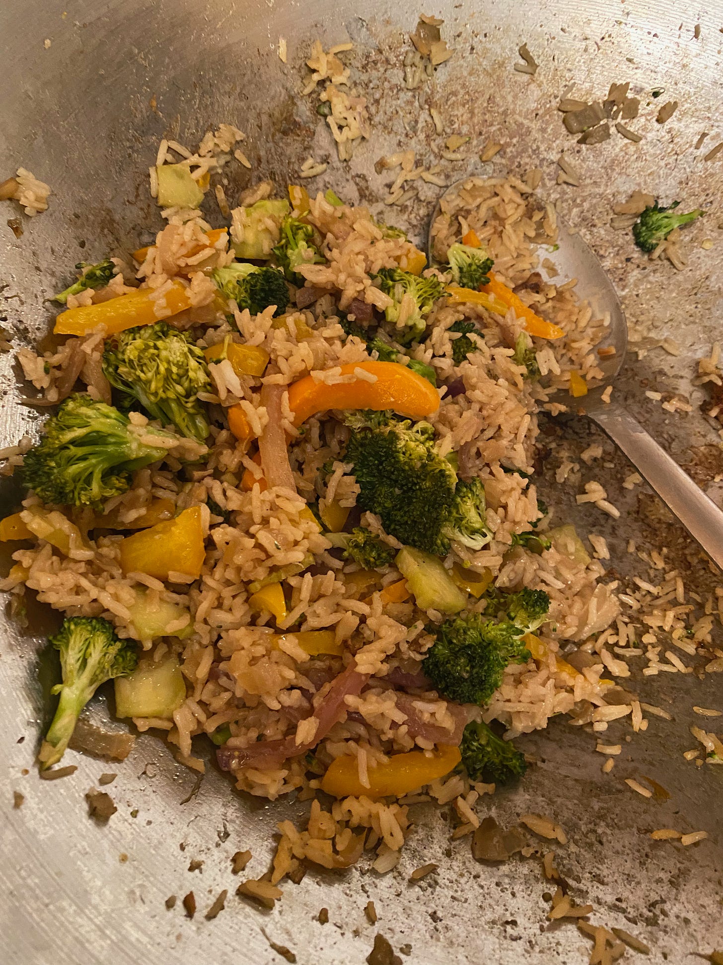 A pile of rice, yellow peppers, and broccoli in a wok.