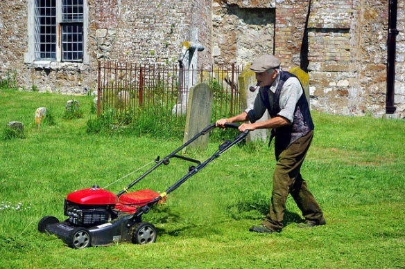 Picture of old man mowing the lawn in church grounds