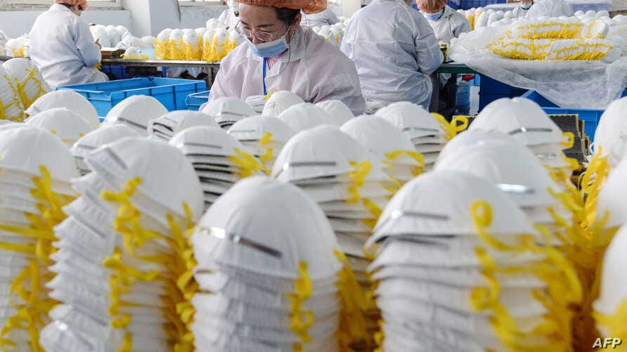 This photo taken on February 28, 2020 shows workers producing face masks at a factory in Handan in China's northern Hebei…