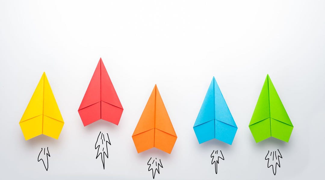 Five colorful paper airplanes rocketing upward to represent getting smaller things done without the burden of too much process.