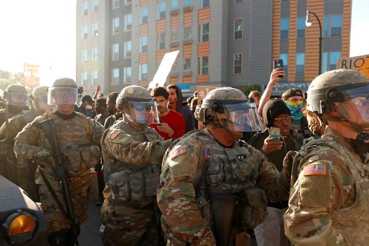 Minnesota National Guard members are seen near protesters in Minneapolis on Friday.