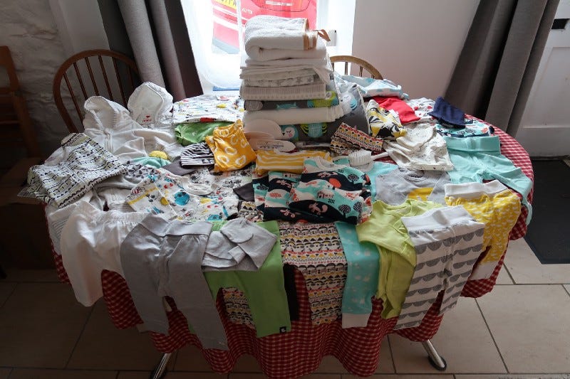 The contents of a Finnish baby box; dozens of items of clothing and accessories.