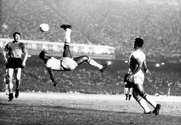 Pelé kicking a ball over his head as two other players look on.