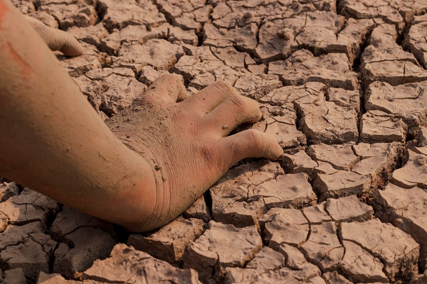 Dirty child's hand in a parched desert