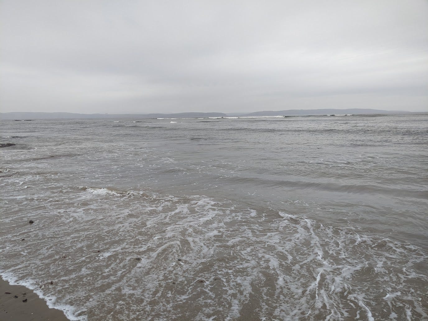 Grey sea with a white frothy frill and grey rain clouds overhead