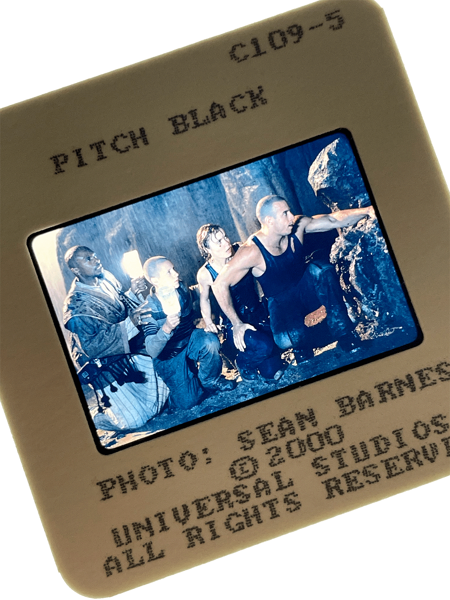A slide from PITCH BLACK showing Vin Diesel, Radha Mitchell, and others crouching in the dark. Photo by Sean Barnes.