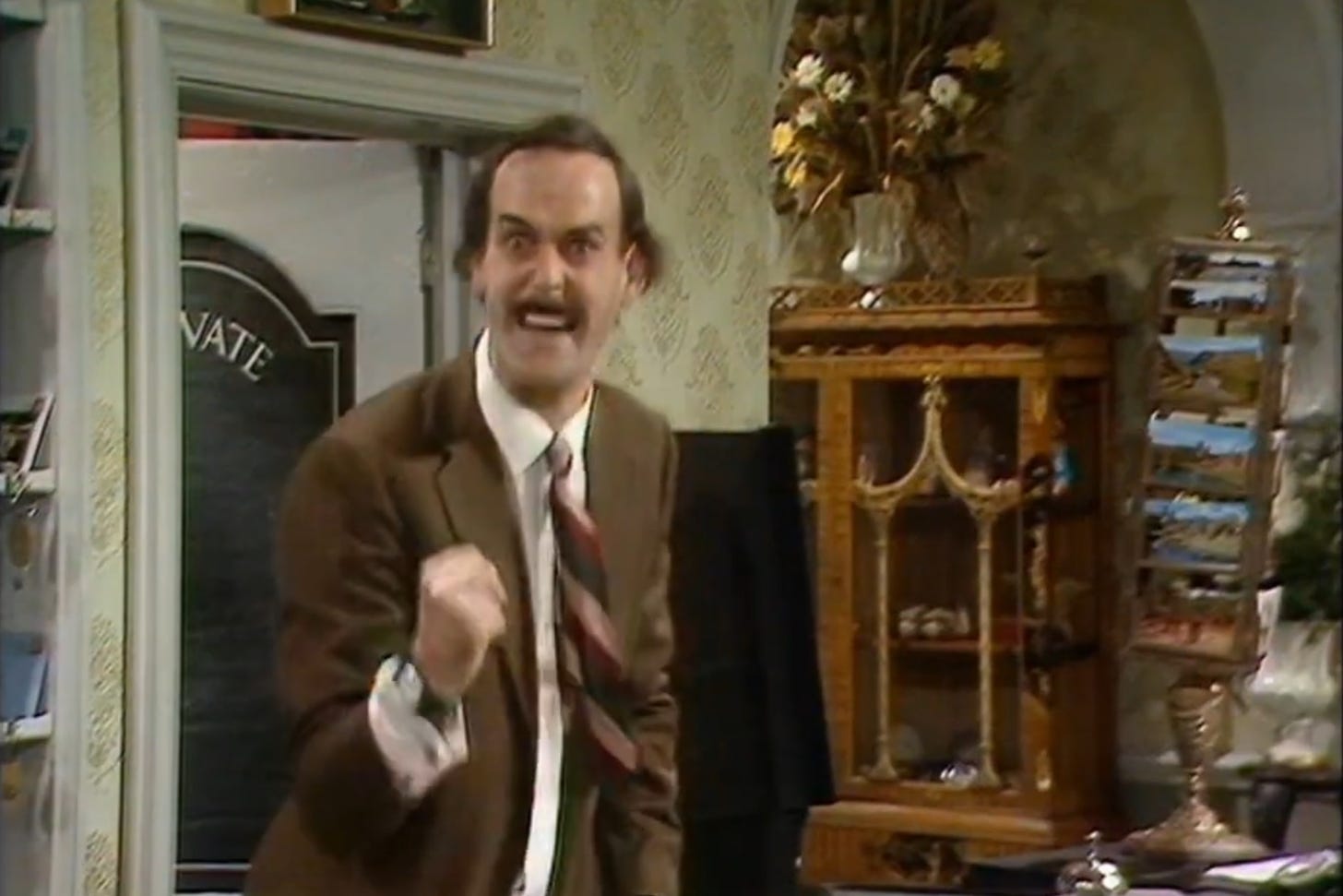 John Cleese with fist clenched playing Basil Fawlty in BBC comedy “Fawlty Towers”