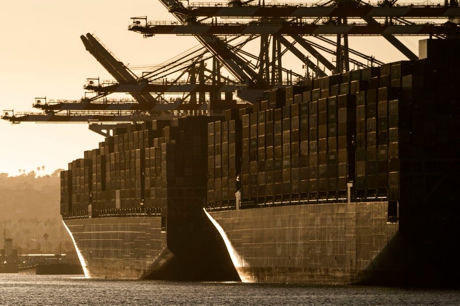 Two large (and full) container ships are seen moored at a port at sunset. Two large (and full) container ships are seen moored at a port at sunset.