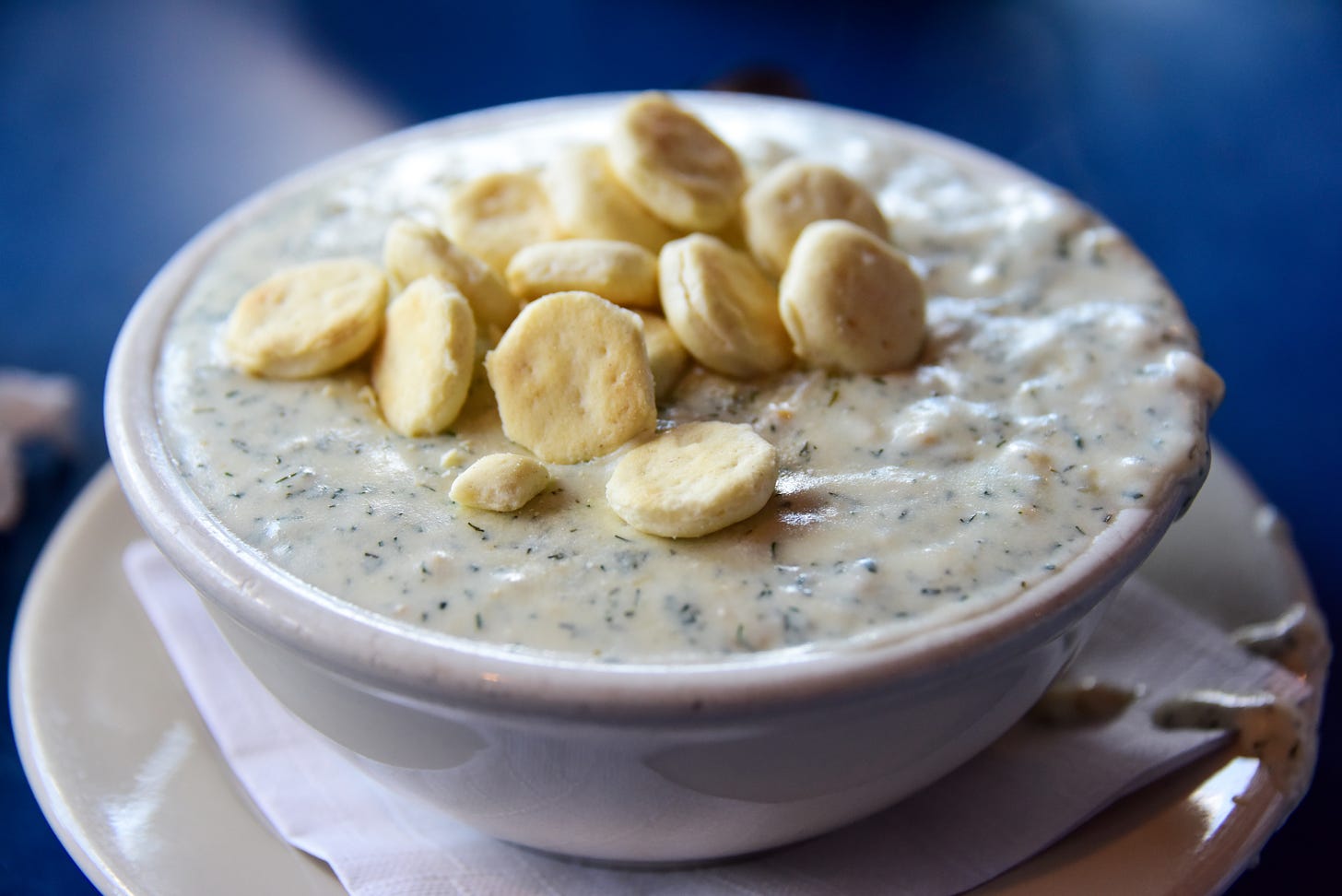 A bowl of clam chowder with a large pile of oyster crackers on top