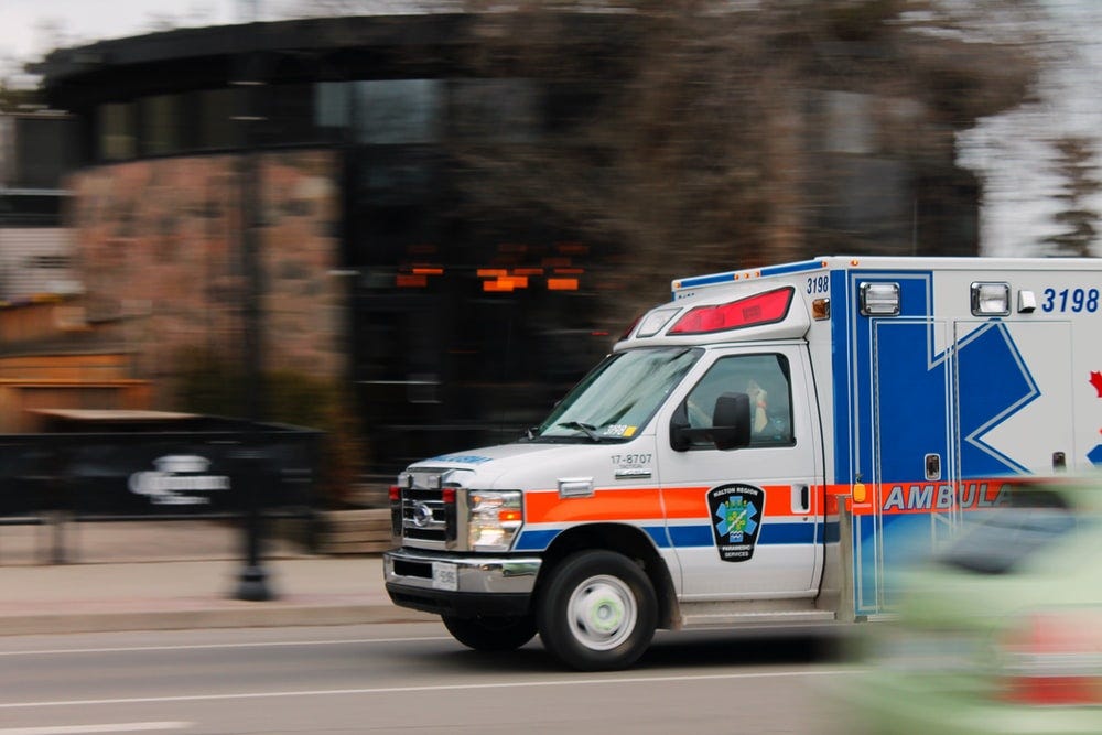 white and blue ambulance van traveling on road