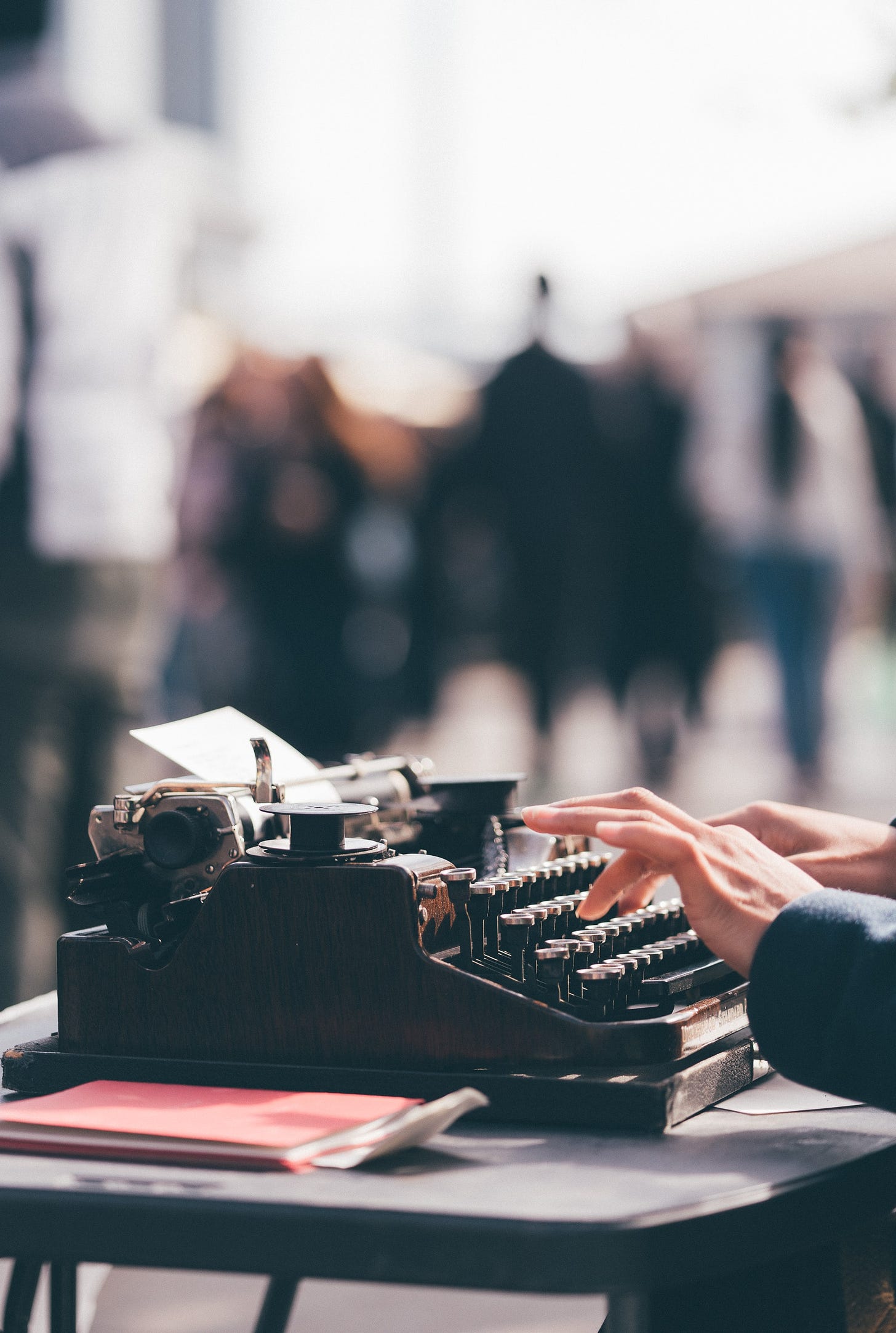 Image of hands typing on an old fashioned typewriter with a blurred background, free from Upsplash
