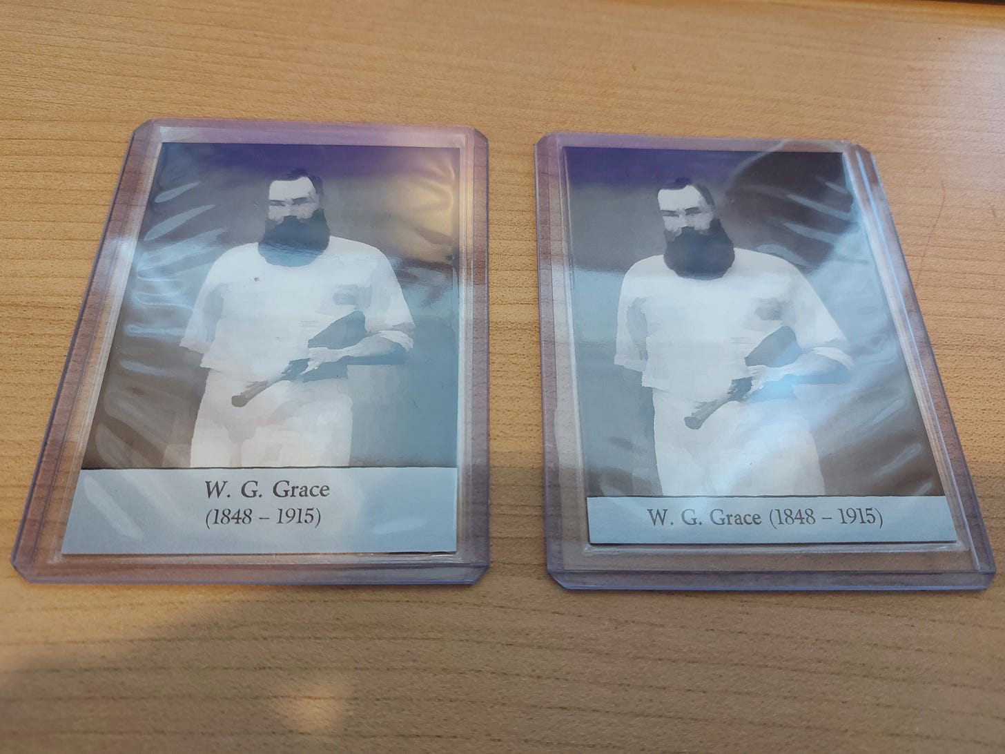 (Card fronts. Final version on the left; prototype on the right). W.G. Grace trading cards on desk; side to side.