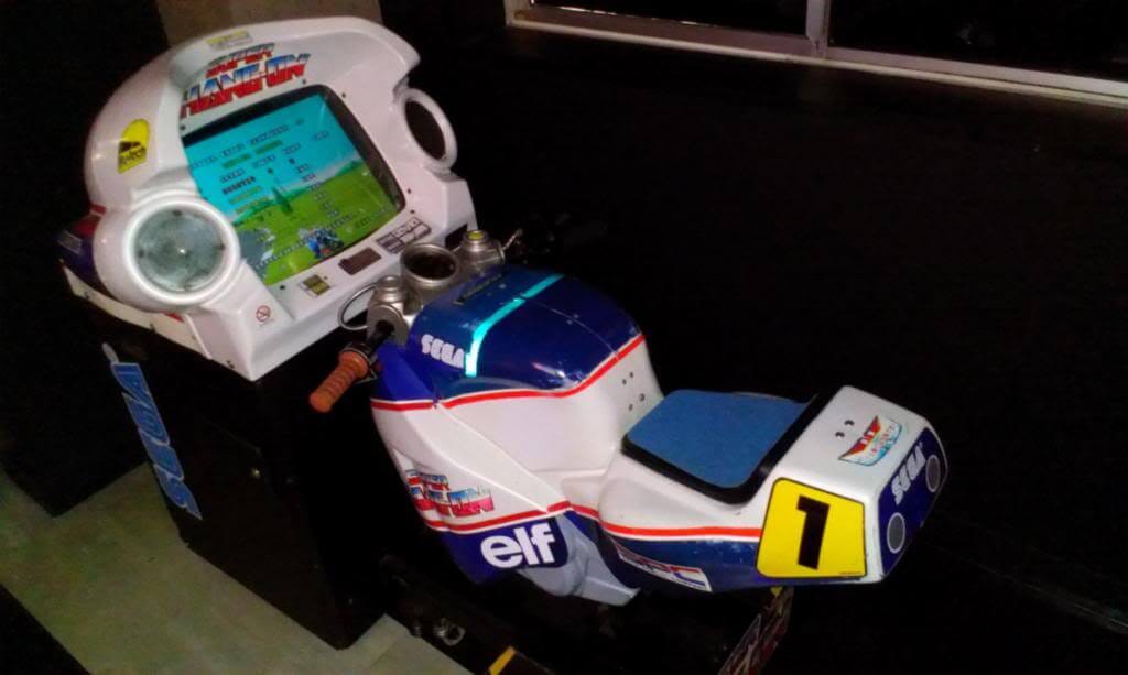 A photo of the Super Hang-on ride-on cabinet as seen from above. The game's logo is also seen above the monitor, which sits directly in front of the "bike"
