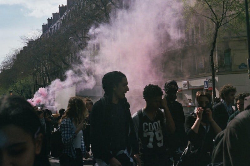 Film photo of Paris during protest with people in foreground and purple smoke in background