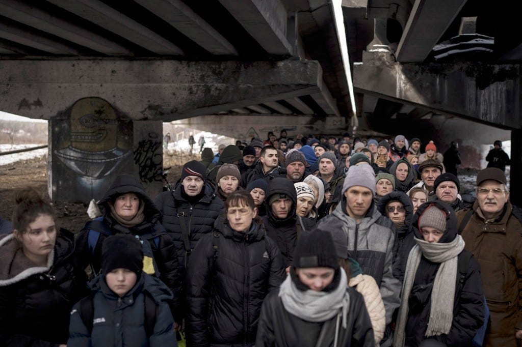 Ukrainians crowd under a destroyed bridge in Irpin.