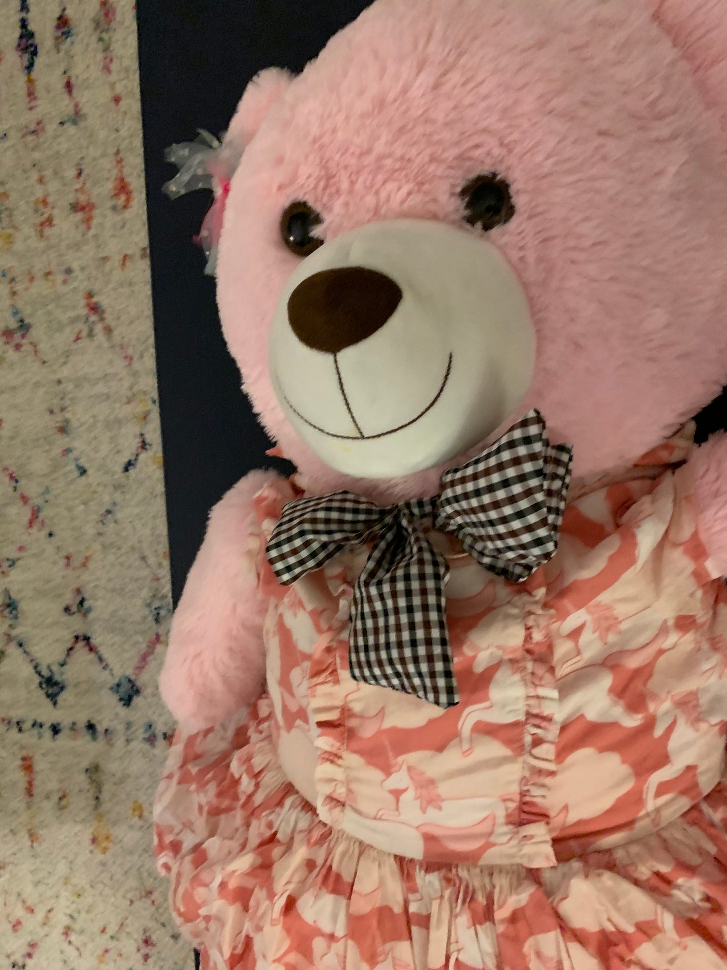 a giant pink teddy bear smiles on a yoga mat